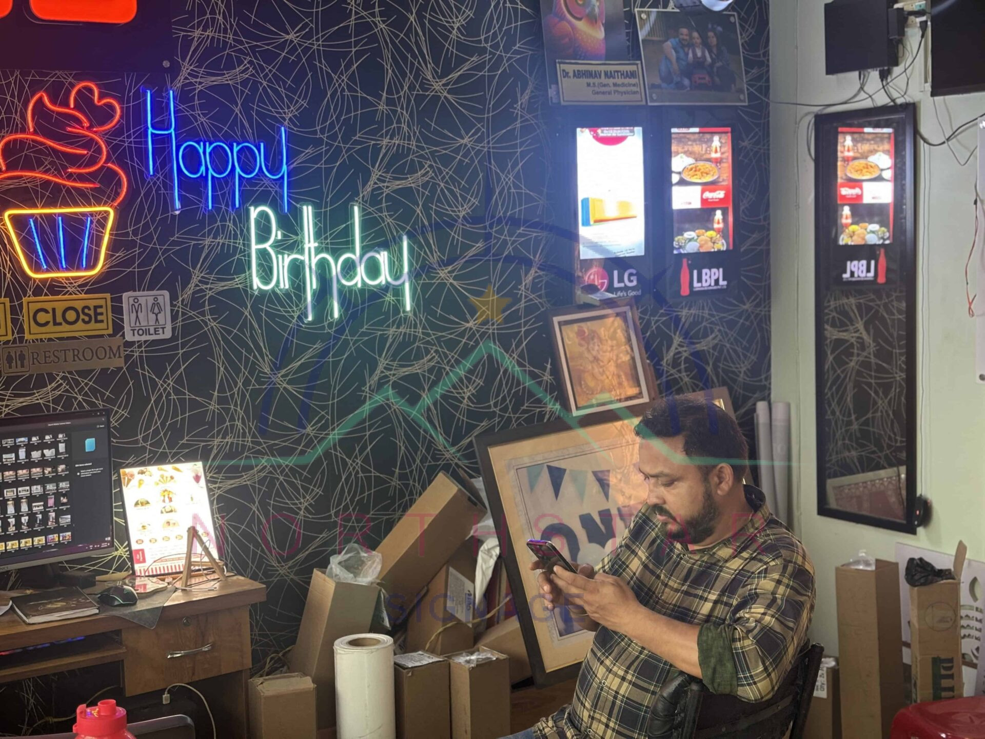 man on phone sitting in a signage shop